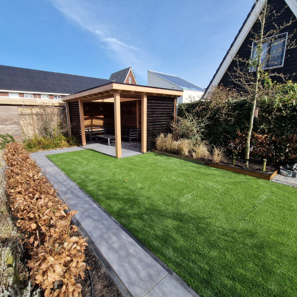 Tuin met kunstgras en overkapping