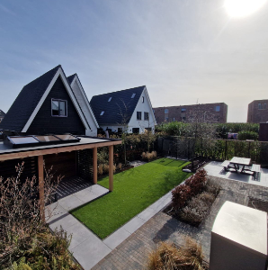 Tuin met overkapping, gras en tegels