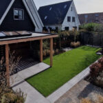 Tuinrenovatie. Tuin met overkapping, kunstgras en bestrating