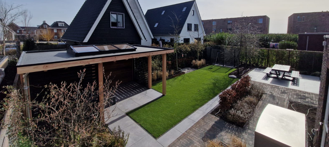 Tuinrenovatie. Tuin met overkapping, kunstgras en bestrating
